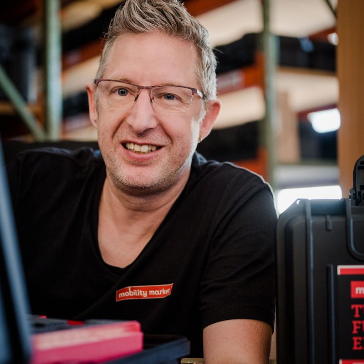 Mitarbeiter von mobility market im Lager, vor sich ein geöffneter Werkzeugkoffer